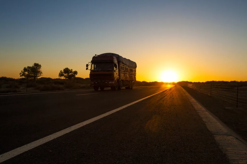 Camión de transporte circulando al amanecer en una carretera desierta